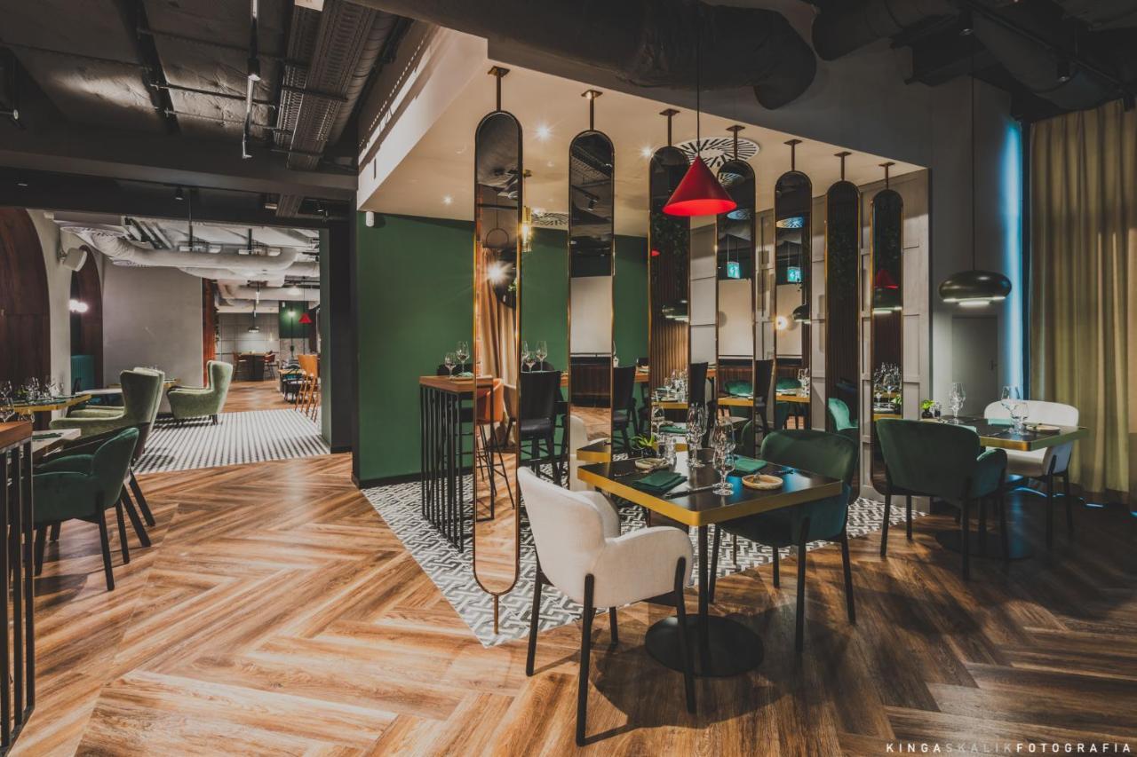 Royal Tulip Warsaw Centre Varsóvia Exterior foto The image depicts a modern restaurant interior. It features a combination of stylish furniture, including green and white chairs around wooden tables. The floor has a distinctive herringbone pattern, and there are mirrors along the walls, adding dept