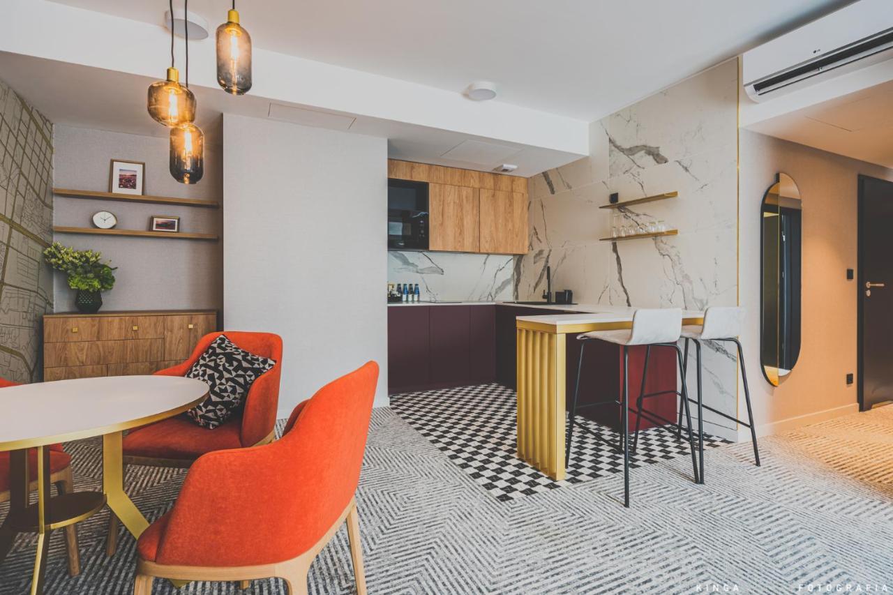 Royal Tulip Warsaw Centre Varsóvia Exterior foto The photo shows a modern interior space, likely a kitchen and dining area. 

- **Kitchen Area**: The kitchen features a combination of wooden cabinets and a dark-colored countertop. There's a marble backsplash that adds a sleek touch. It has an open 