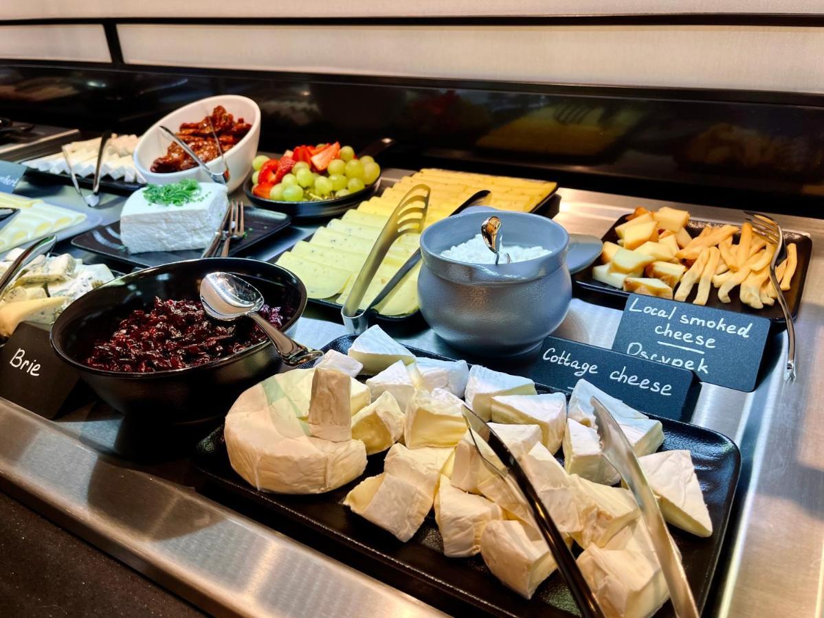 Royal Tulip Warsaw Centre Varsóvia Exterior foto The photo shows a variety of cheeses and accompaniments arranged on a buffet display. There are several types of cheese, including Brie and a soft cheese that appears to be cottage cheese. There's also a bowl of dark-colored cheese, likely a spread. 